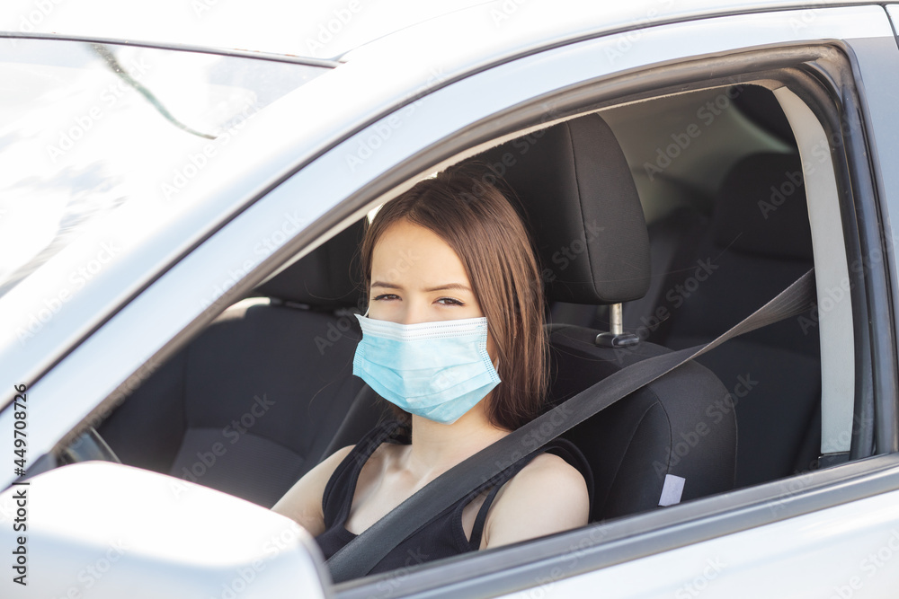 driving in mask,young teenager woman at the wheel goes with protection from covid-19