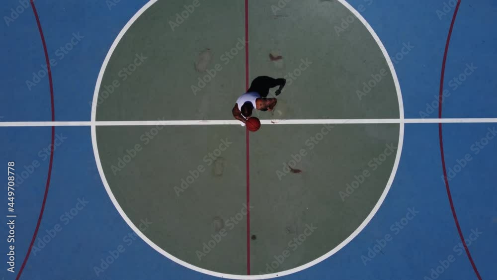 Toma aerea de drone en 4k de chico joven en pista de baloncesto en exterior