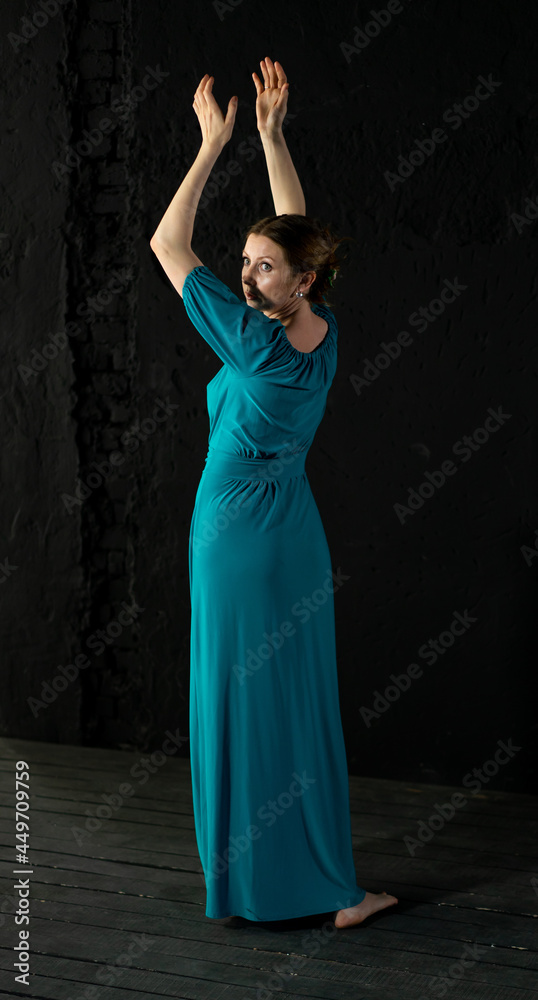 woman in blue-green long dress on black background dancing woman in blue-green long dress on black background dancing