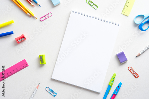 Flat lay colorful school supplies and paper notepad on white background. Back to school concept. Top view with copy space