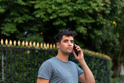 Young latin man in the park talking by mobile phone.