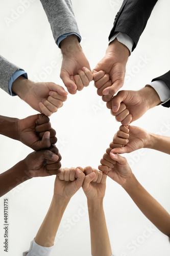 Close up crop vertical image of diverse multiethnic people join fists hands in circle show unity. Multiracial employees or friends involved in teambuilding activity. Teamwork, diversity concept.