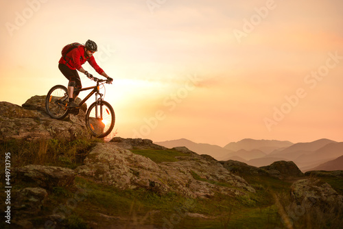 Fototapeta Naklejka Na Ścianę i Meble -  Cyclist in Red Riding Bike on the Summer Rocky Trail at Sunset. Extreme Sport and Enduro Biking Concept.