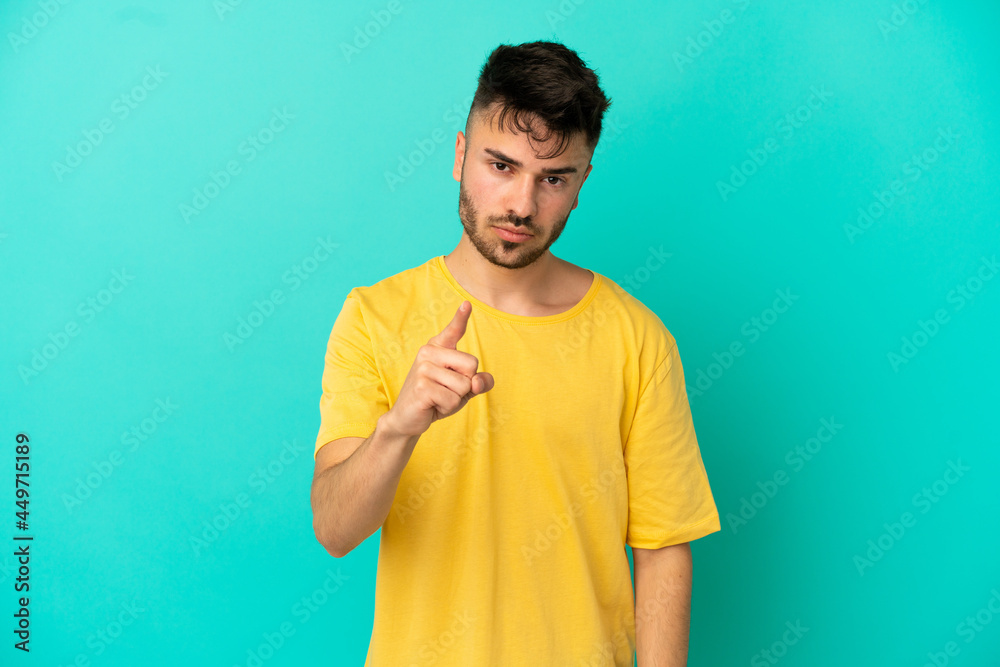 Young caucasian man isolated on blue background frustrated and pointing to the front Young caucasian man isolated on blue background frustrated and pointing to the front