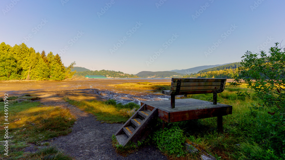 Raised viewing platform and bench overlooking mudflats during low tide for Burrard Inlet on Shoreline Trail at Port Moody - early summer morning during heatwave Raised viewing platform and bench overlooking mudflats during low tide for Burrard Inlet on Shoreline Trail at Port Moody - early summer morning during heatwave