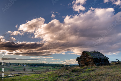 Fotomural Rustic weathered log cabin with dramatic evening sky
