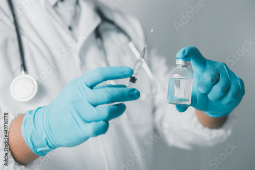 A doctor or scientist in a medical research laboratory holding a syringe containing a liquid vaccine analyzes an antibody sample to boost the patient's immunity. 
