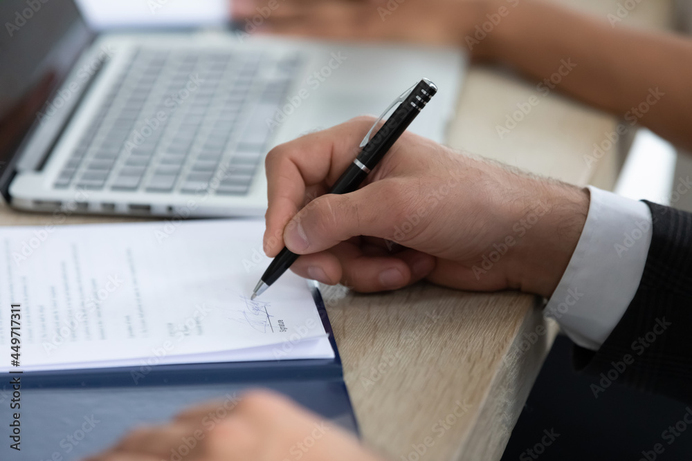 Fototapeta premium Crop close up of male employee or client put signature on document make agreement with business partner at meeting. Businessman sign paperwork close deal at negotiation with customer in office.