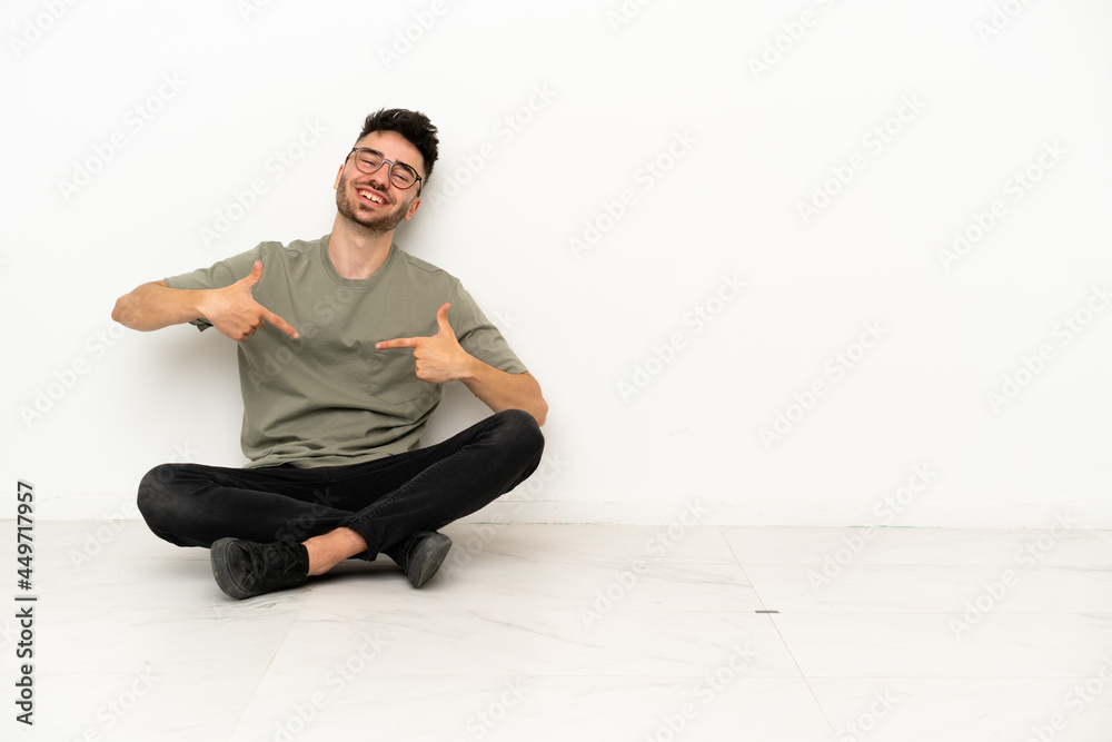 Young caucasian man sitting on the floor isolated on white background proud and self-satisfied Young caucasian man sitting on the floor isolated on white background proud and self-satisfied