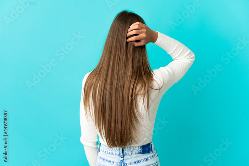 Young woman over isolated blue background in back position and thinking © luismolinero