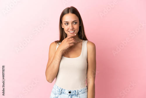 Young woman over isolated pink background looking to the side and smiling