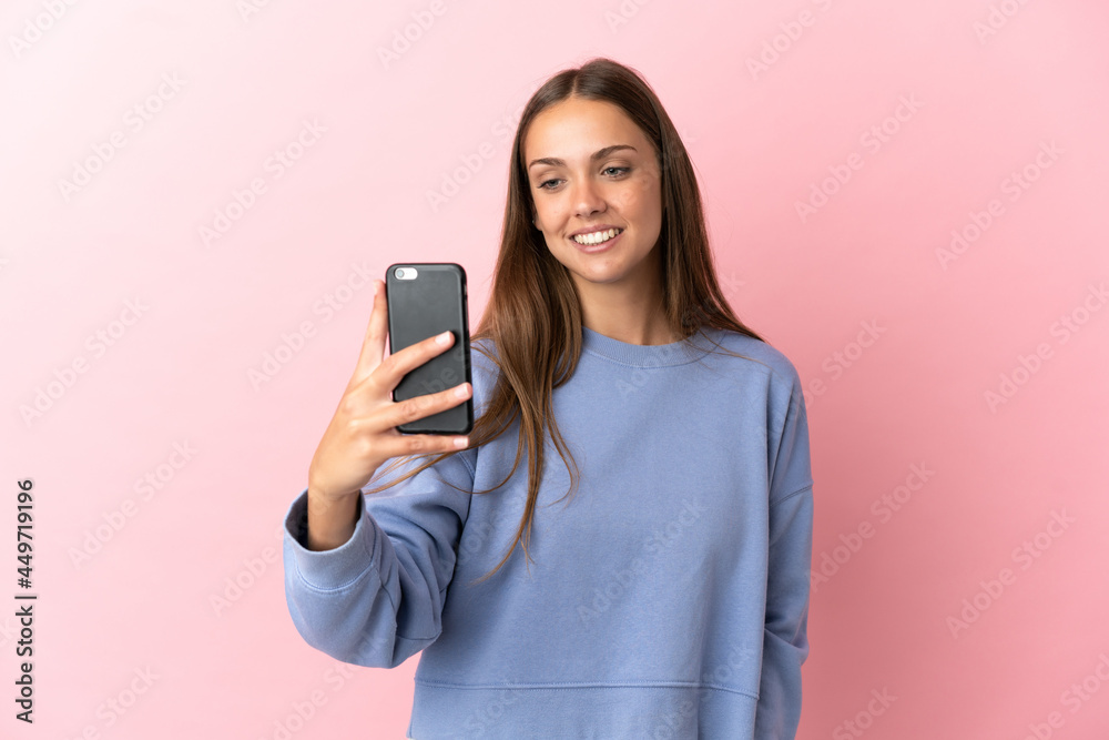 Fototapeta premium Young woman over isolated pink background making a selfie