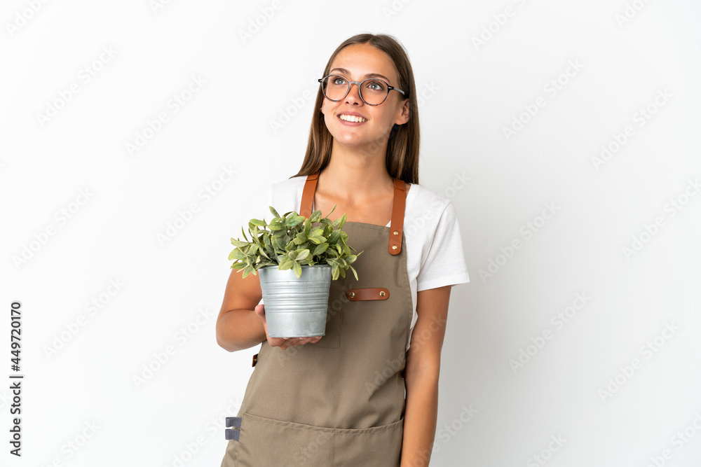 Gardener girl holding a plant over isolated white background thinking an idea while looking up Gardener girl holding a plant over isolated white background thinking an idea while looking up