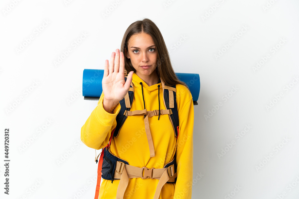 Young mountaineer woman with a big backpack over isolated white background making stop gesture Young mountaineer woman with a big backpack over isolated white background making stop gesture