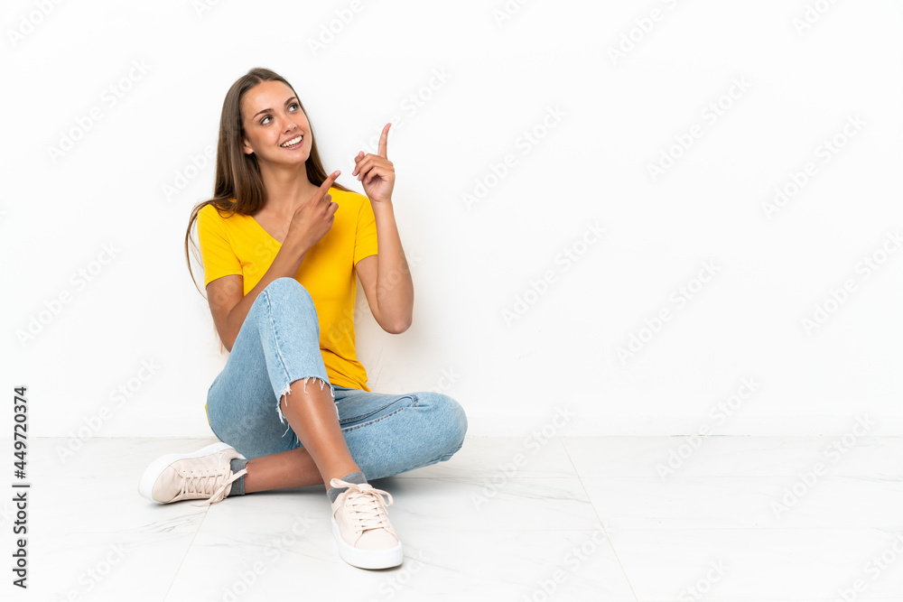 Young girl sitting on the floor pointing with the index finger a great idea Young girl sitting on the floor pointing with the index finger a great idea