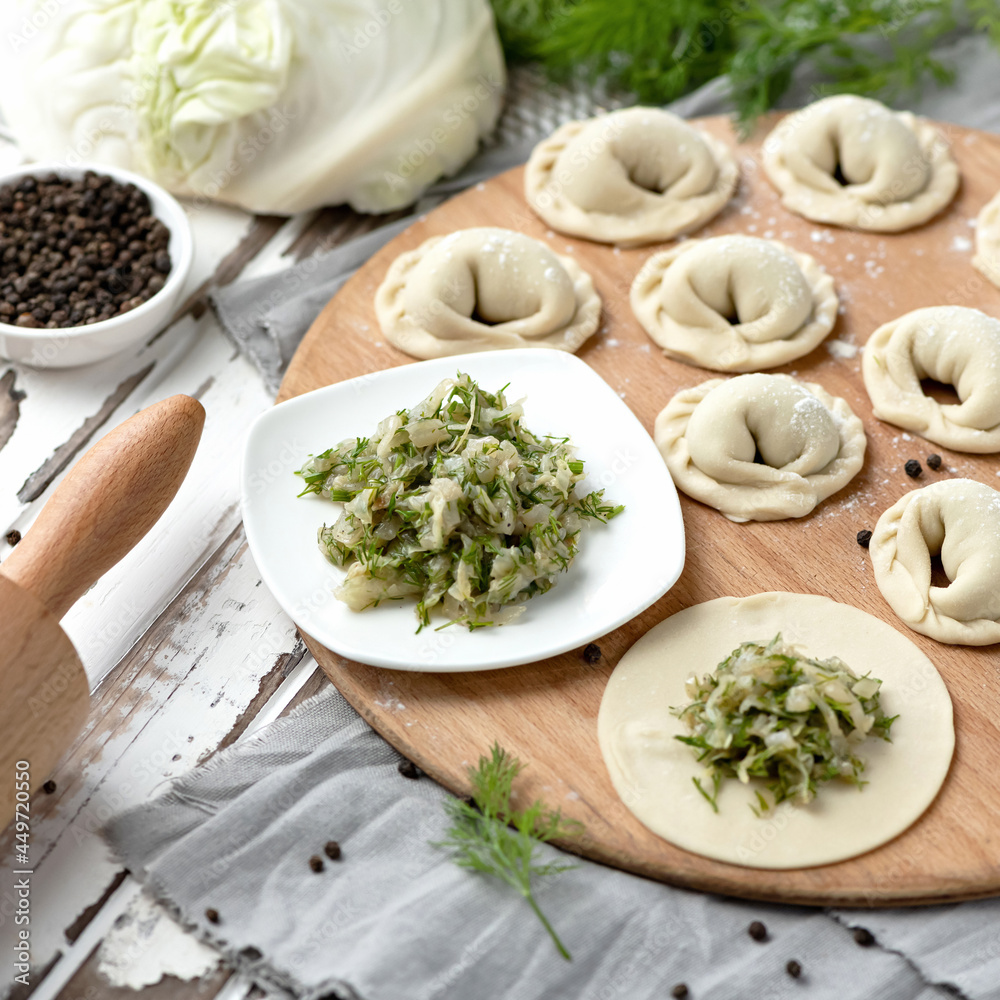 Raw dumplings, dough stuffed with cabbage and dill on wooden table. Vegetarian convenience food. Cooking Process. Raw dumplings, dough stuffed with cabbage and dill on wooden table. Vegetarian convenience food. Cooking Process.