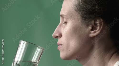 Woman is drinking water. Female hand bring glass with clear water to their mouth and drink it with her eyes closed. Close-up. High quality FullHD footage. 25FPS, downscaling photo