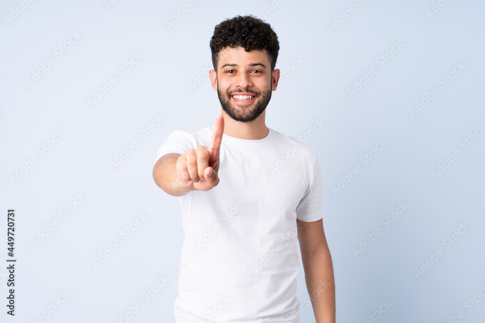 Young Moroccan man isolated on blue background showing and lifting a finger Young Moroccan man isolated on blue background showing and lifting a finger