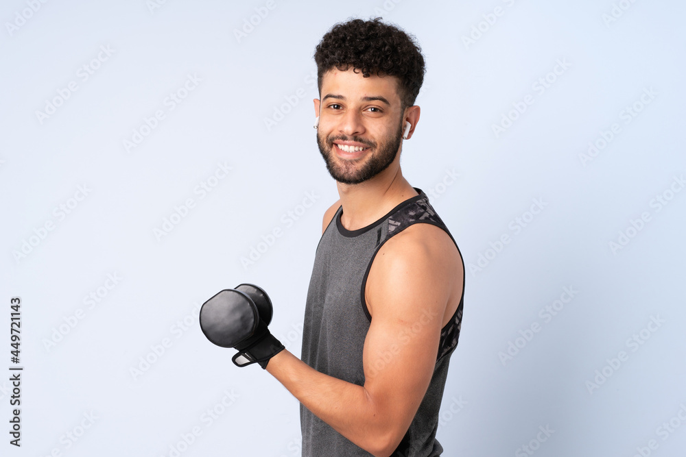 Young Moroccan man isolated on blue background making weightlifting