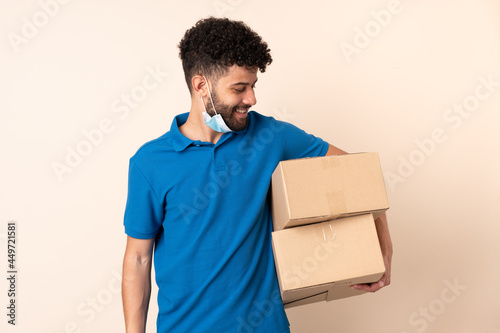 Young delivery Moroccan man isolated on beige background with happy expression