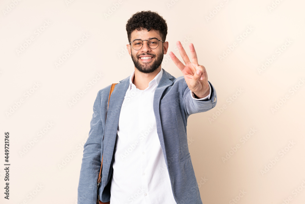 Young business Moroccan man isolated on beige background happy and counting three with fingers