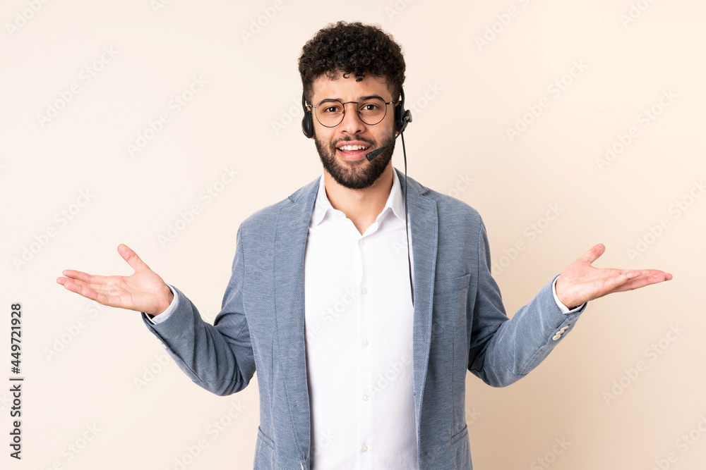 Telemarketer Moroccan man working with a headset isolated on beige background with shocked facial expression