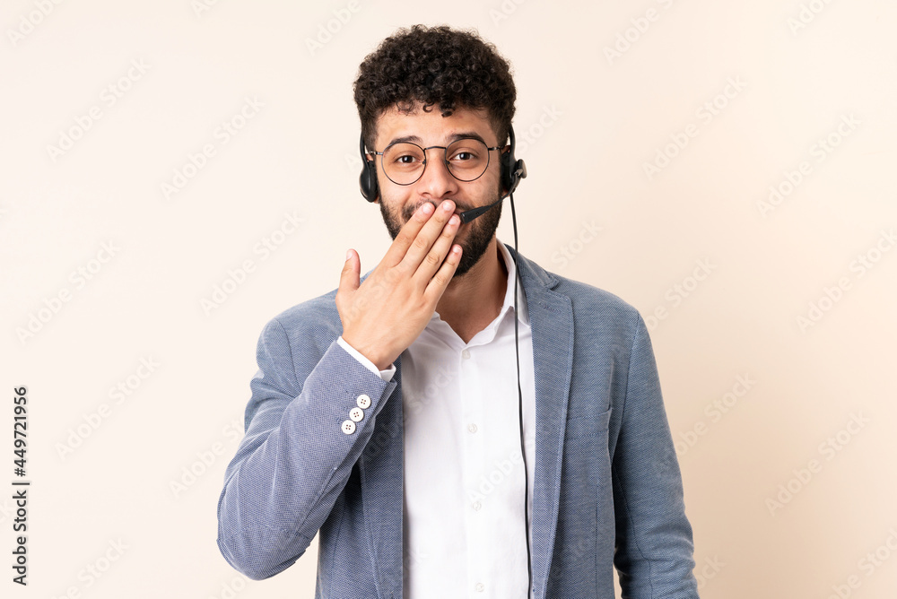 Telemarketer Moroccan man working with a headset isolated on beige background happy and smiling covering mouth with hand Telemarketer Moroccan man working with a headset isolated on beige background happy and smiling covering mouth with hand