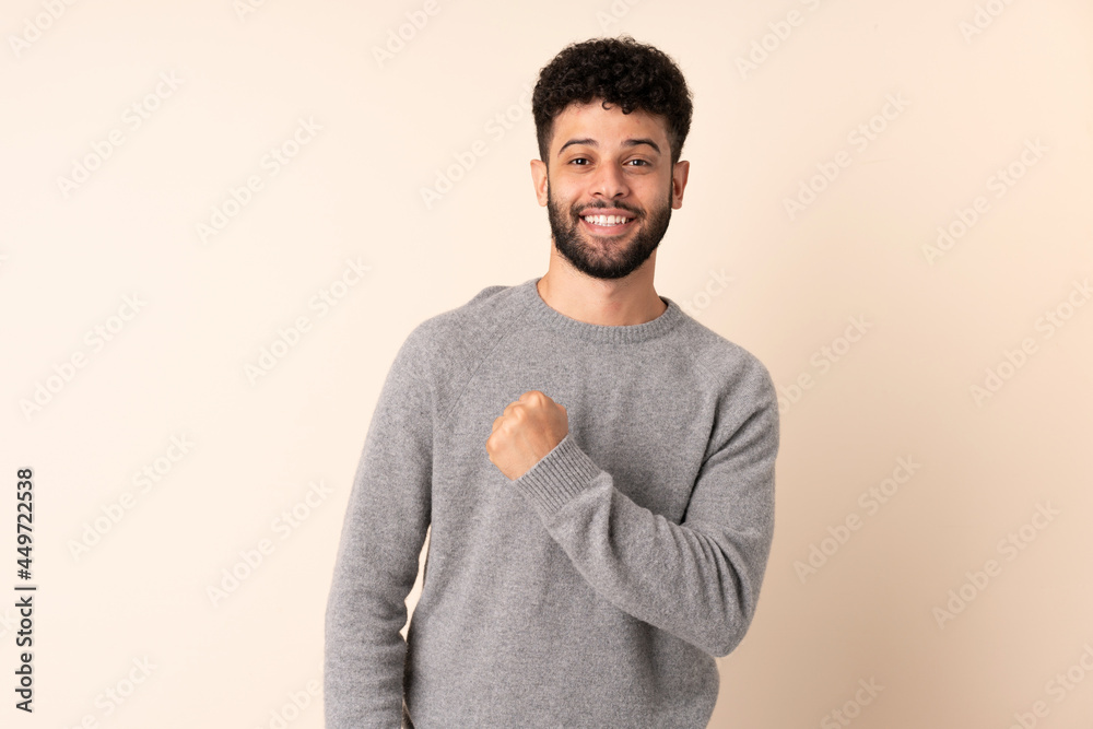 Young Moroccan man isolated on beige background celebrating a victory