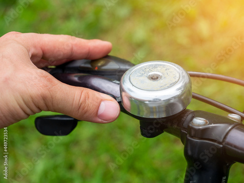 Close-up of a man's hand pressing an old metal bicycle bell