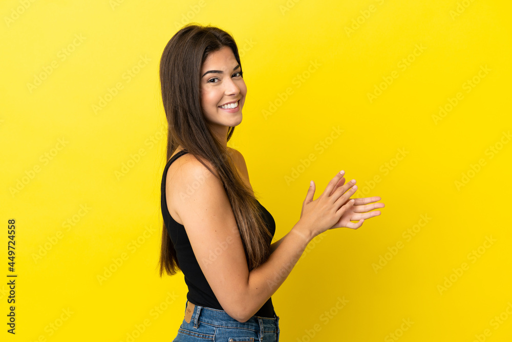 Young Brazilian woman isolated on yellow background applauding