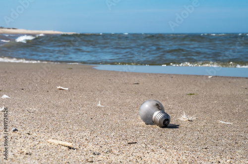 Garbage on the beach. A glass bulb on the seashore. Pollution of the coast.