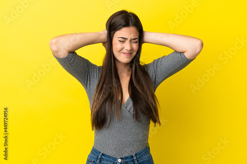 Young Brazilian woman isolated on yellow background frustrated and covering ears