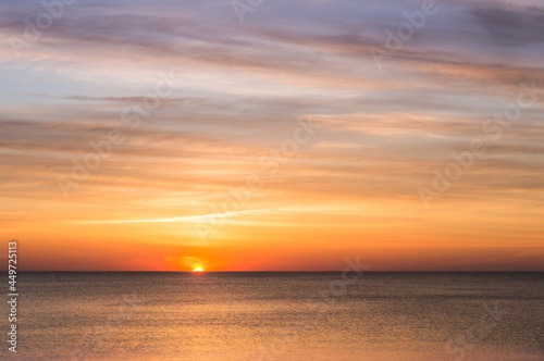 Sunset over the sea. Reflection of sunlight in the sea waves. Red and yellow sky in the rays of the sunset.