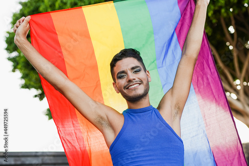 Transgender man with make up holding lgbt rainbow flag in the city - LGBTQIA concept