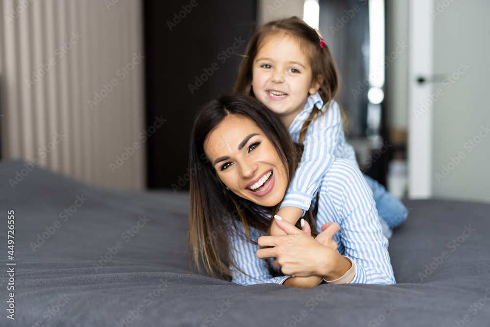 Young mother playing with her daughter on the bed at home Young mother playing with her daughter on the bed at home