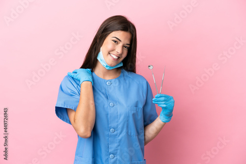 Dentist woman holding tools isolated on pink background laughing