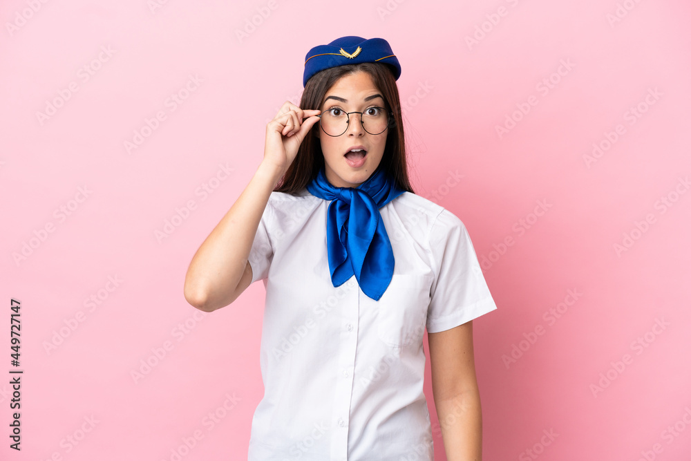 Airplane stewardess Brazilian woman isolated on pink background with glasses and surprised Airplane stewardess Brazilian woman isolated on pink background with glasses and surprised