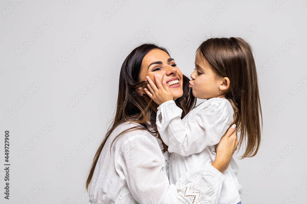 Portrait of little daughter kissing her beautiful happy mother isolated on white background Portrait of little daughter kissing her beautiful happy mother isolated on white background