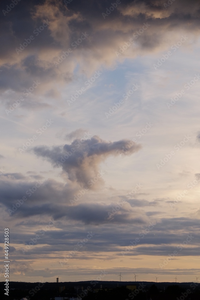 Wolken am Himmel damatische Stimmung abends Unwetter mit Horizont und Windräder Sillhouette Hochformat