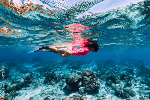 Konstfotografi Woman in pink lycra with freediving fins swimming in blue ocean.