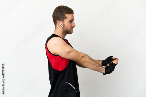 Handsome blonde man over isolated white background stretching arm