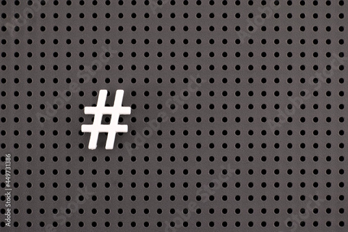 White Hashtag symbol on gray pegboard photo
