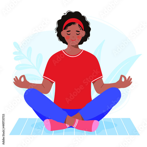 Young dark-skinned woman meditates while sitting on a yoga mat.