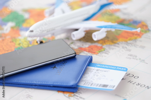 Smartphone with passport and tickets and an airplane lie on geographic map closeup