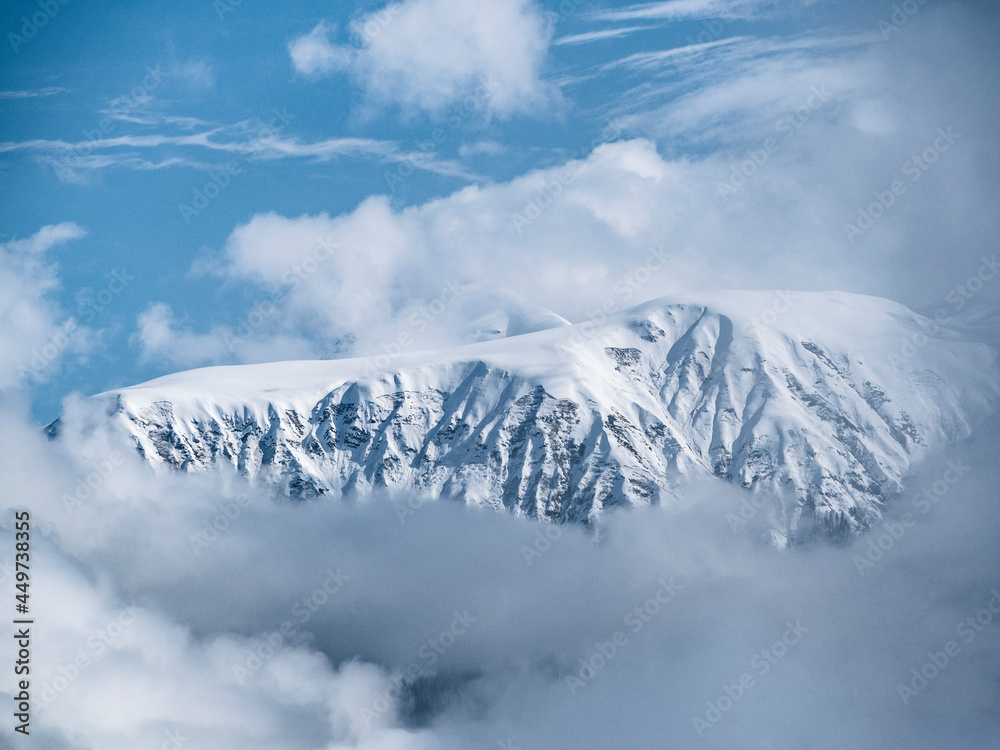 Natural background of mountains in clouds at blue sky background