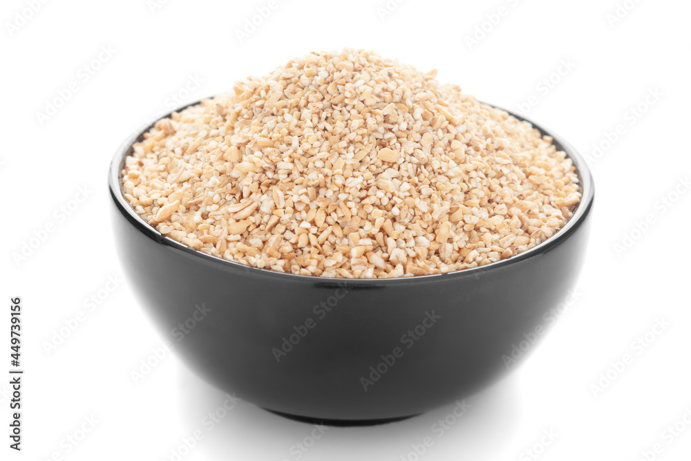 Close-Up of organic broken wheat (dalia or daliya ) roasted in black ceramic bowl over white background Close-Up of organic broken wheat (dalia or daliya ) roasted in black ceramic bowl over white background