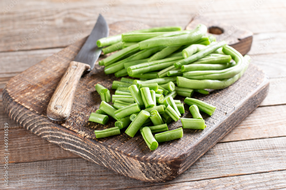 Green string beans, green beans slices on a cutting board on a wooden table. Green string beans, green beans slices on a cutting board on a wooden table.
