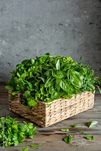 A bouquet of various garden aromatic herbs, herbs and spices in a wicker basket on wooden background for cooking, aromatherapy.