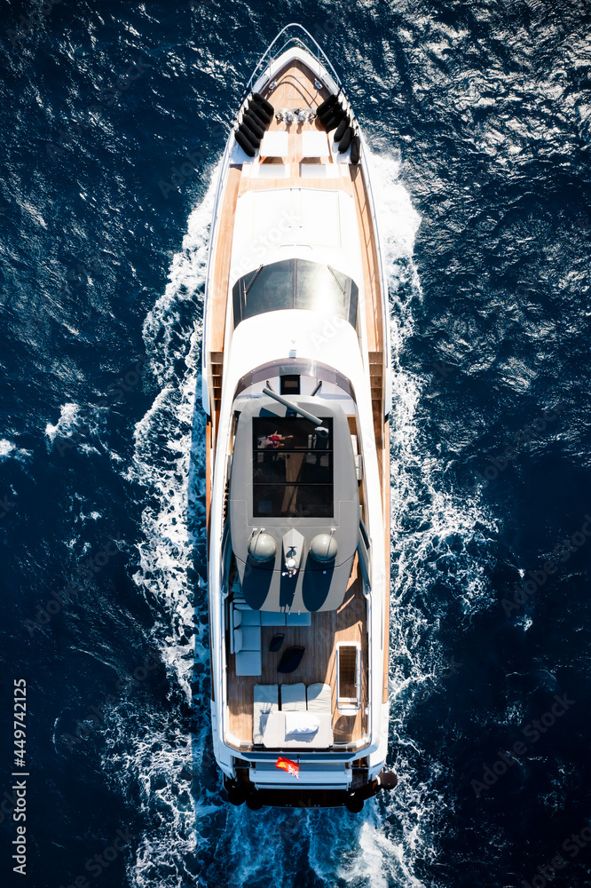 View from above, stunning aerial view of a luxury yacht cruising on a blue water creating a wake.Sardinia, Italy.