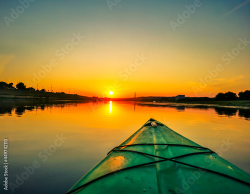 View of front of kayak, floating on the river at sunset